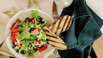 Ein Salat mit Gegrilltem Brot und einer Gabel auf einer Marmortafel.