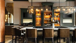 A bar area with a central island, bar stools, and a well-stocked liquor cabinet. - Renaissance Boulder FlatIron Hotel (Broomfield)