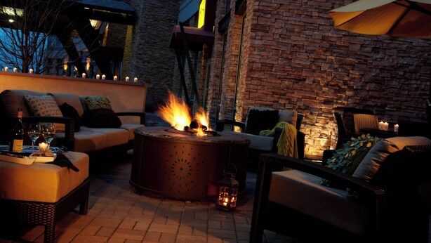 A cozy outdoor seating area with a fire pit, comfortable seating, and a brick wall backdrop. - Renaissance Boulder FlatIron Hotel (Broomfield)