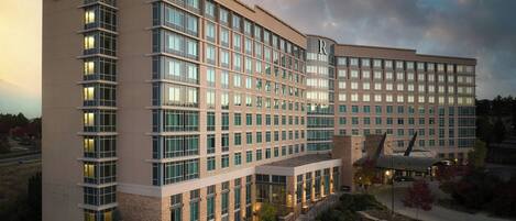 A modern hotel with multiple floors, large windows, and a prominent entrance area with outdoor seating.