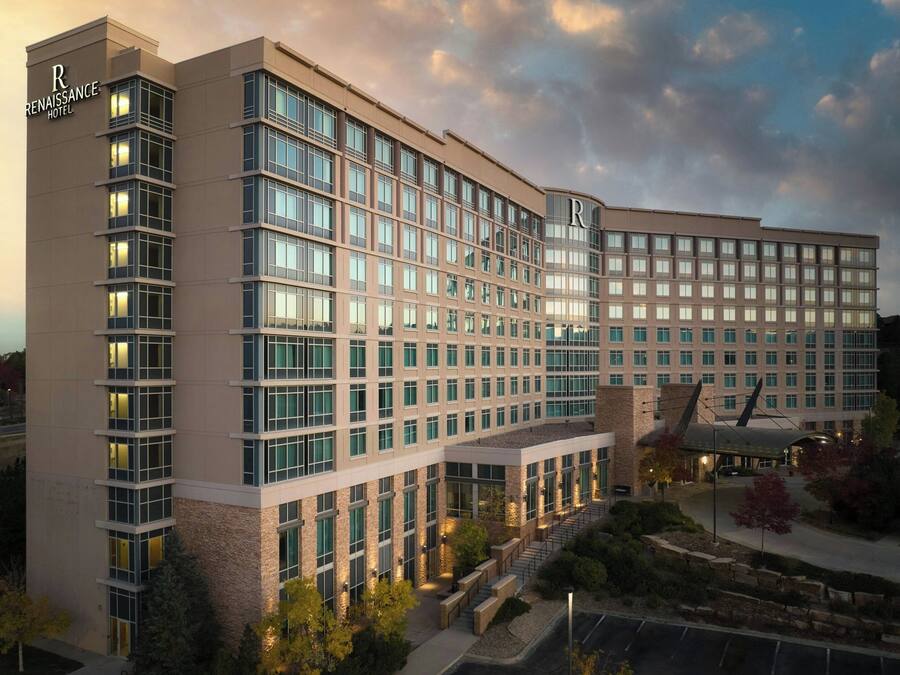 A modern hotel with multiple floors, large windows, and a prominent entrance area with outdoor seating.