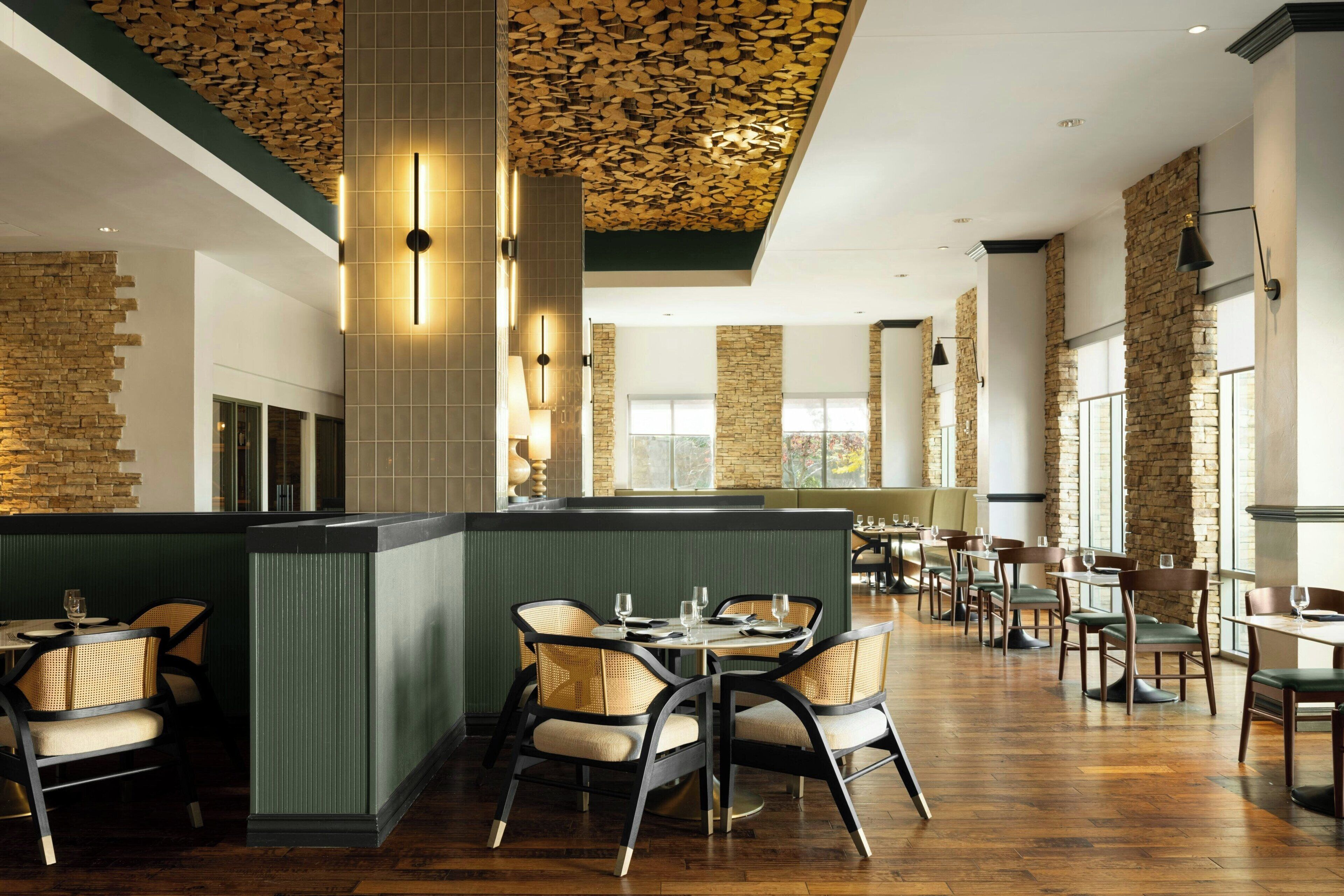 Un restaurant avec un mur en briques, un plafond en bois et de nombreuses tables et chaises.