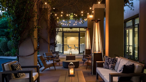 An outdoor seating area with modern furniture, a central table with a candle, and ambient lighting.