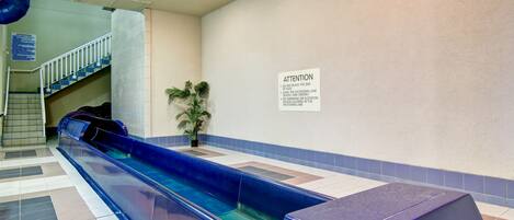 A pool area with a blue water slide, a staircase, and a sign with instructions.