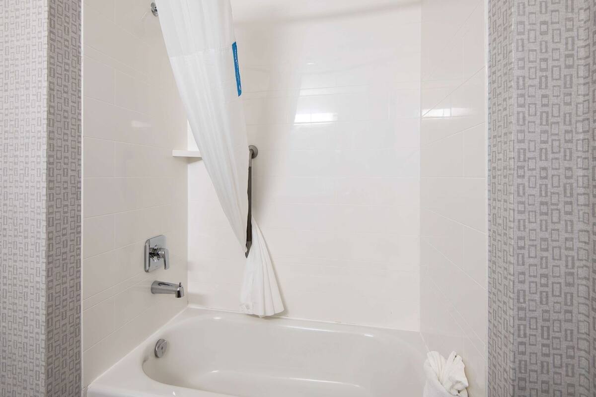 Un baño con bañera, cortina de ducha y toallero.