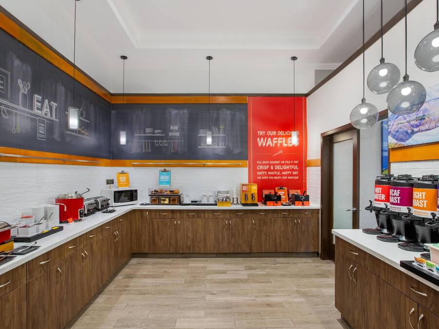 Een moderne keuken met een pannenkoekenstation, koffiezetapparaten en een schoolbord met keukengerei.