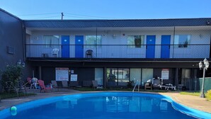 A building with a swimming pool, a balcony with blue railings, and a sign indicating pool regulations. - 7 Nights Stay (Niagara Falls)