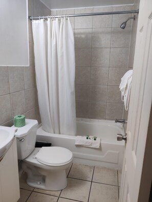 A bathroom with a toilet, bathtub, shower curtain, and a towel rack.