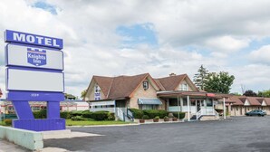 A motel with a sign indicating it's Knights Inn, featuring a brick facade, a covered entrance, and a parking lot. - Knights Inn London (London)