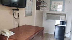 A room with a flat-screen TV, a telephone, a refrigerator, an air conditioning unit, and a wall-mounted coat rack. - Knights Inn London (London)