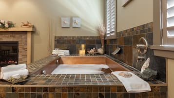 Bathroom features a bathtub, fireplace, and stone-tiled floor.