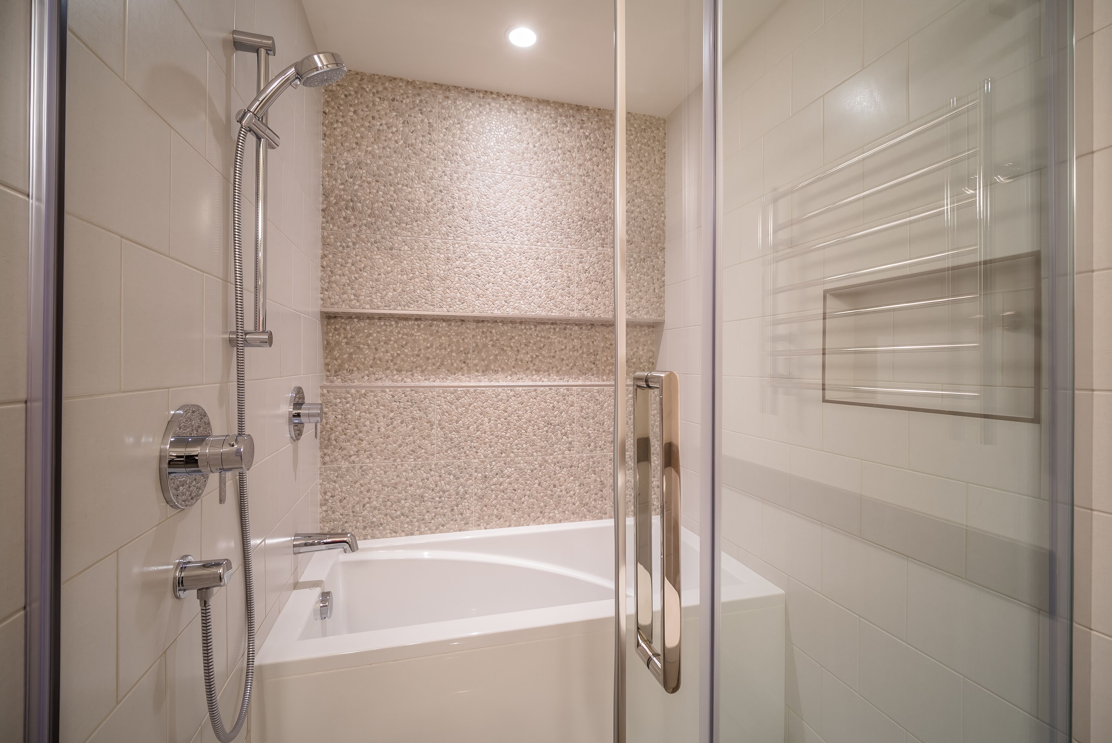 Un baño moderno con cabina de ducha de vidrio, una bañera y una puerta de vidrio.