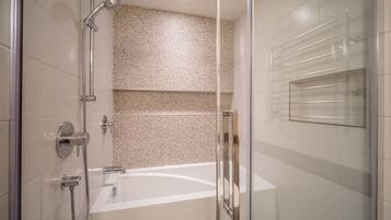 Un baño moderno con cabina de ducha de vidrio, una bañera y una puerta de vidrio.