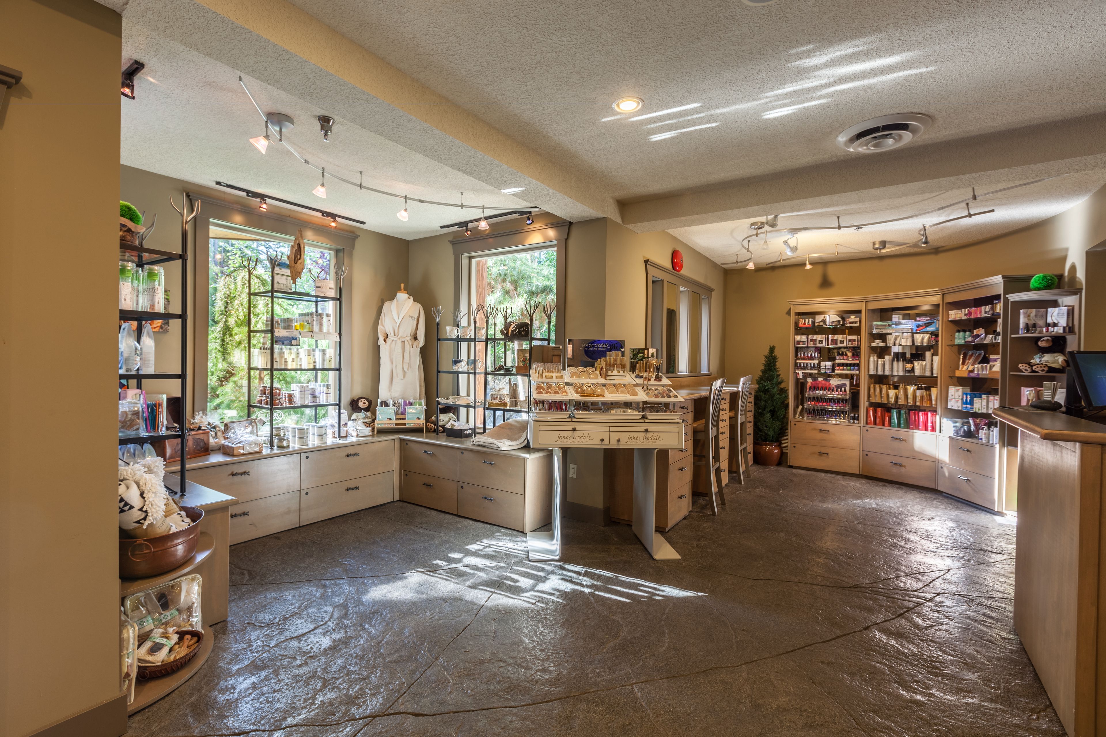 A spacious room with a large window, a wooden counter, and shelves with various items.