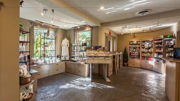 A spacious room with a large window, a wooden counter, and shelves with various items.