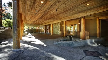 A covered outdoor area with wooden beams, stone flooring, and a water feature.
