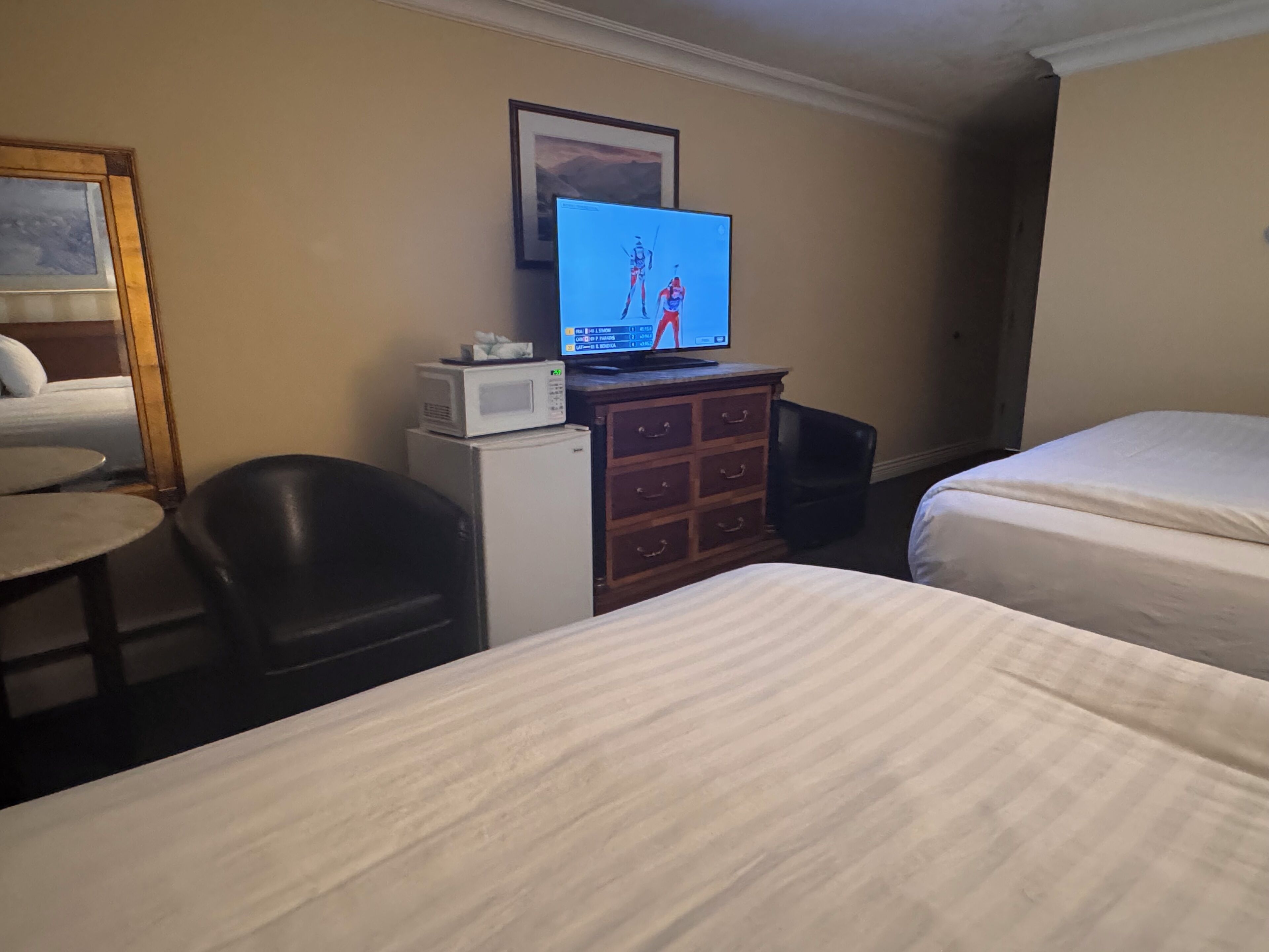Een hotelkamer met twee bedden, een televisie, een magnetron, een tafeltje en een stoel.