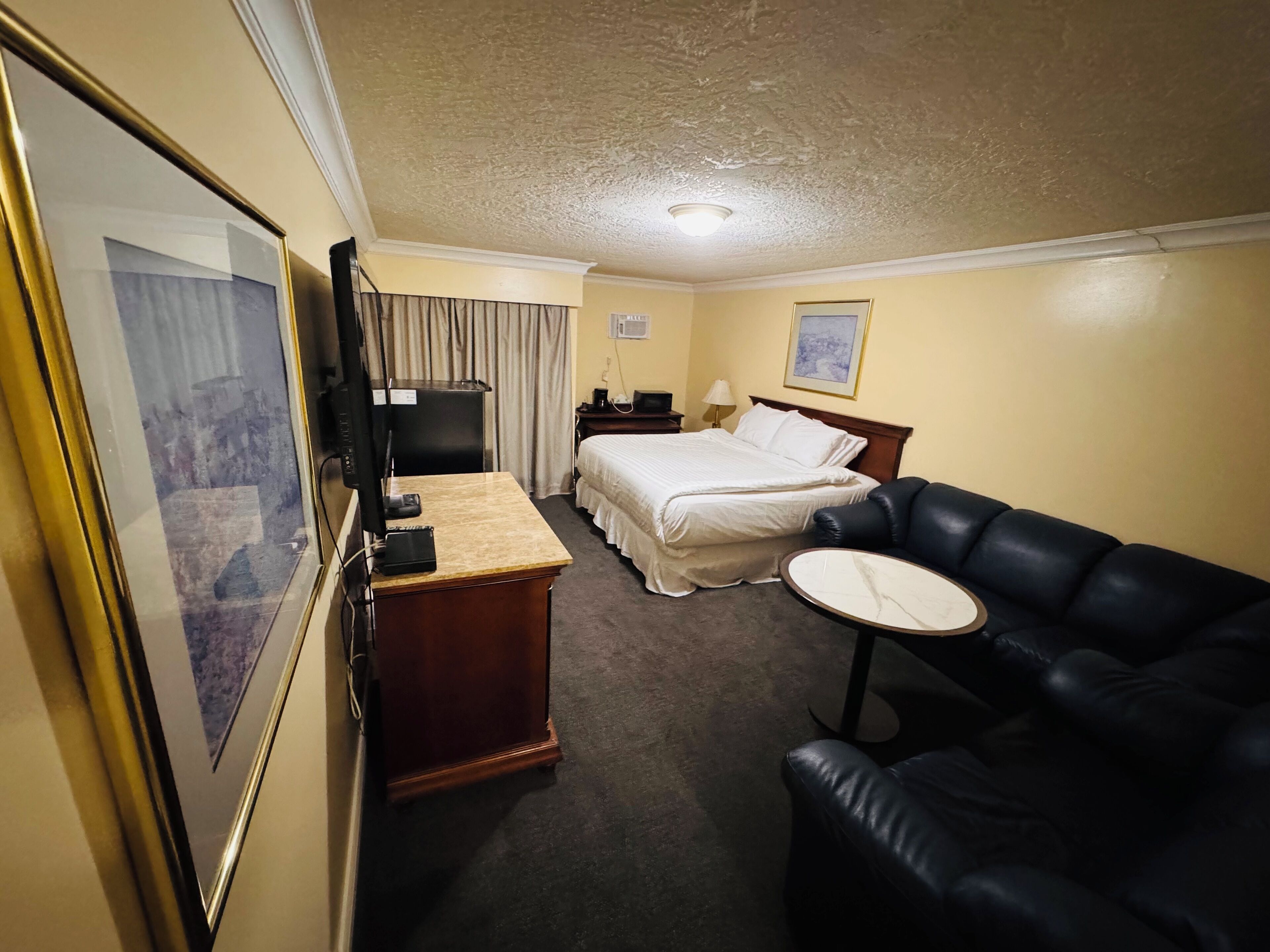 Une chambre d’hôtel équipée d’un lit, d’un bureau, d’une chaise, d’une télévision et d’une petite table.