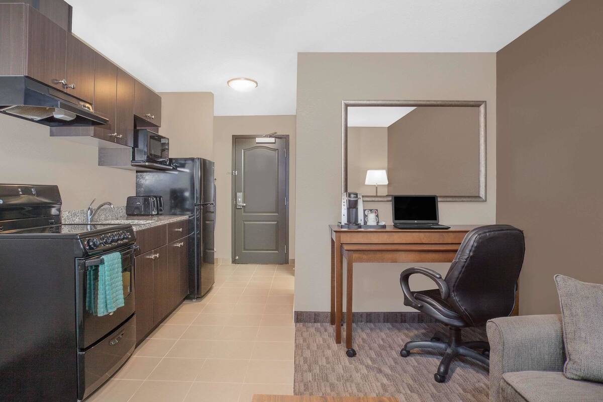 A compact kitchen with modern appliances, a dining area with a table and chair, and a small seating area with a couch.
