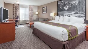 A hotel room with a large bed, a desk with a computer, a chair, a couch, and a large window with curtains. - Super 8 by Wyndham Athabasca AB (Athabasca)