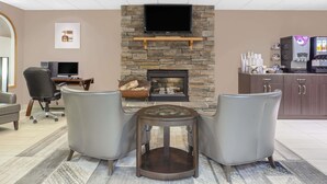 A modern lounge area with a stone fireplace, comfortable seating, and a coffee station. - Super 8 by Wyndham Athabasca AB (Athabasca)