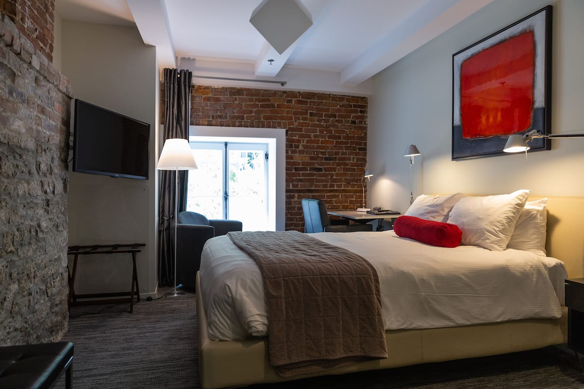 A hotel room with a bed, a desk, a chair, a TV, and a large window.
