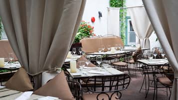An outdoor dining area with tables and chairs, some with cushions.
