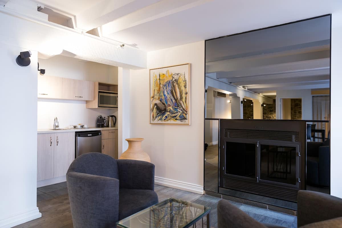 A modern living room with a fireplace, a dining area, and a kitchen.