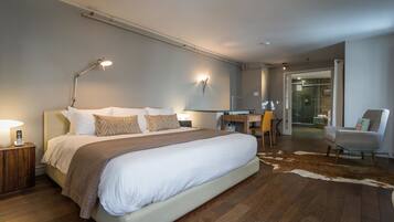 Una habitación de hotel moderna con una cama grande, un escritorio, una silla y una zona de ducha de vidrio.