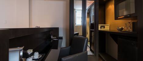 A compact kitchen with a coffee machine, a small dining area with a chair, and a microwave.