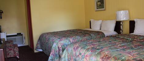 A hotel room with two beds, a desk, and a chair.