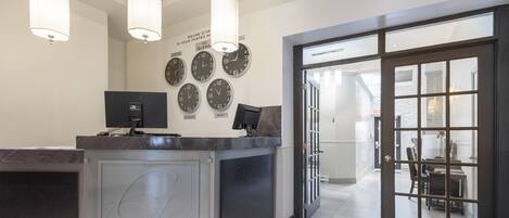 A reception area with a marble counter, multiple clocks, and a modern interior design.
