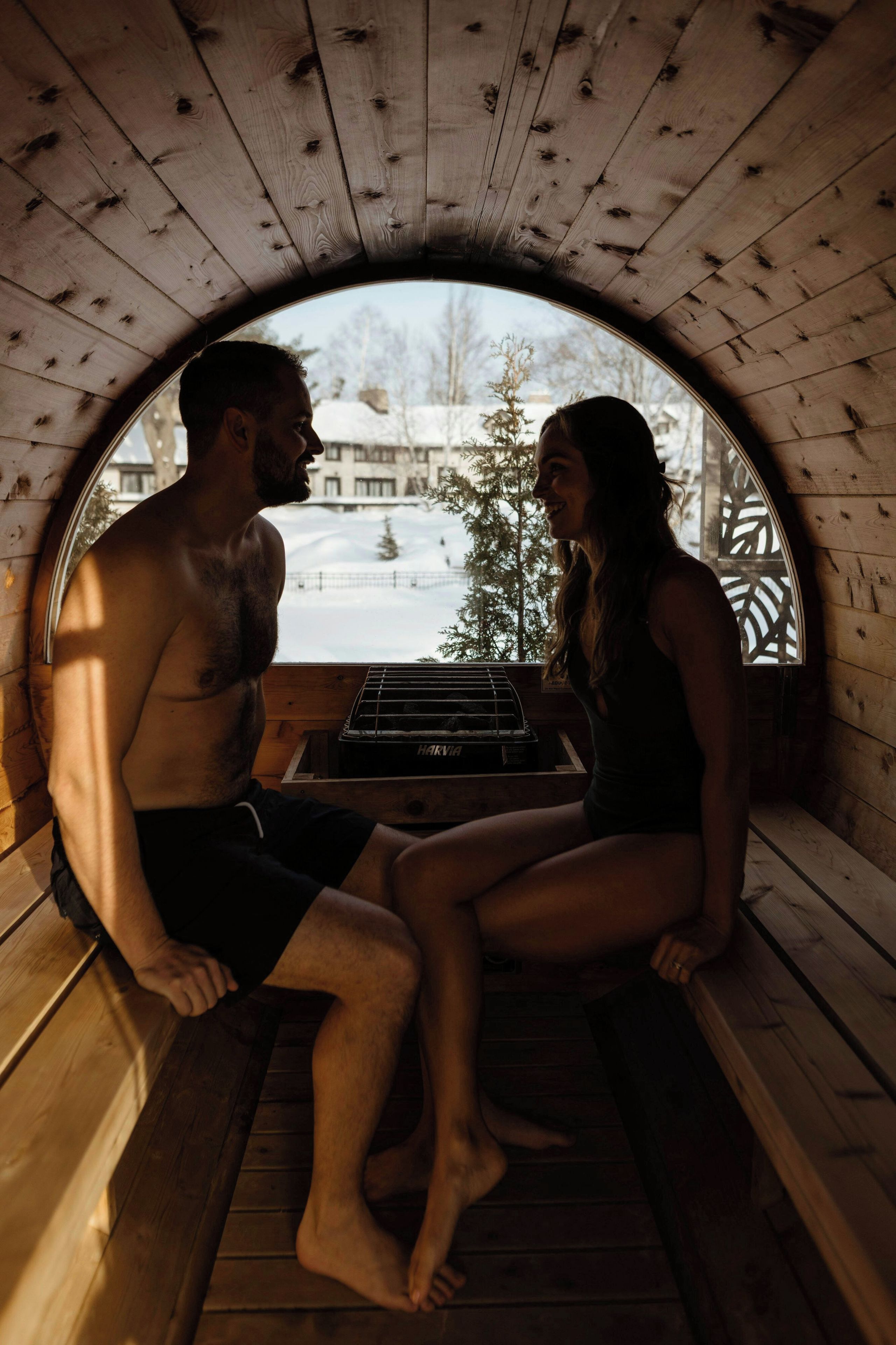 A sauna with a wooden interior and a view of a snowy landscape.
