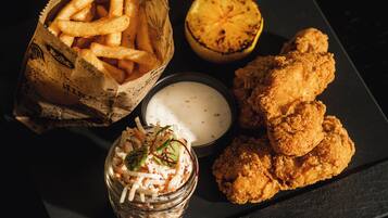 Une assiette contenant du poulet frit, des frites, un demi-citron grillé et une petite portion de salade de chou.