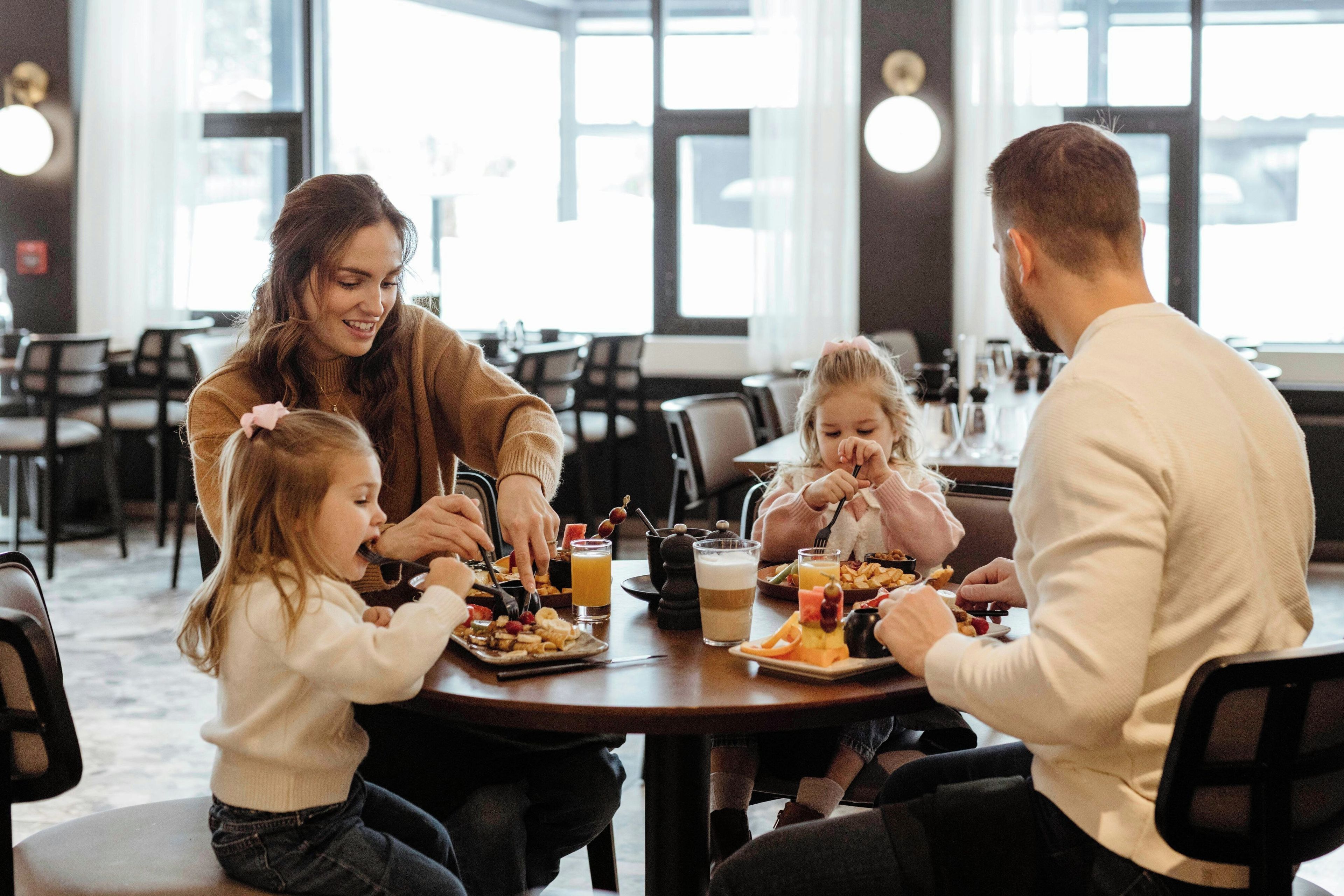 A family dining at a restaurant with a modern interior, large windows, and a casual setting.