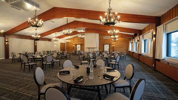 A conference room with multiple tables and chairs, wooden paneling, and chandeliers.