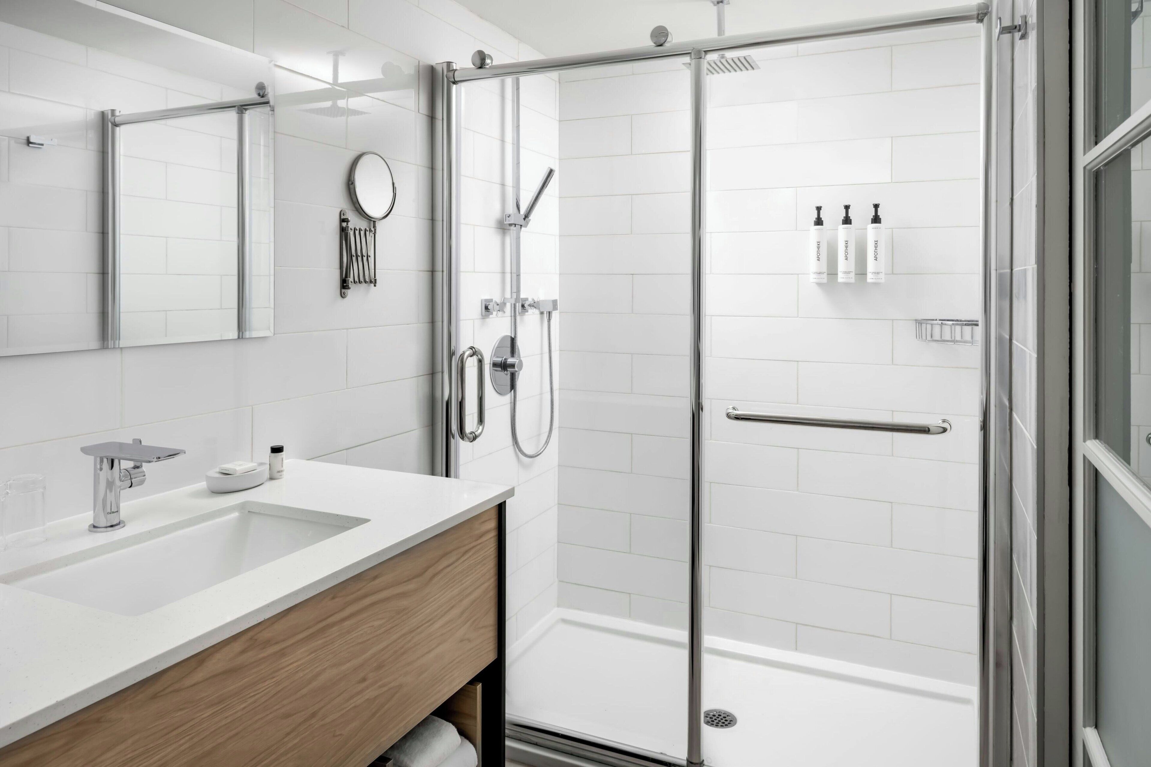 Une salle de bain moderne avec une douche à parois de verre, un lavabo blanc et un meuble-lavabo en bois.