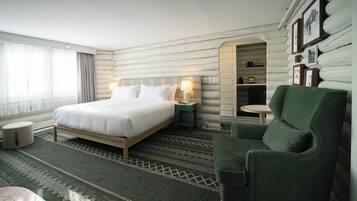Una habitación de hotel con una cama, un sillón verde, una mesita y una pared decorada con cuadros.