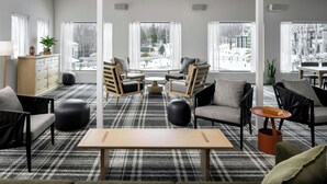 A modern living room with a plaid carpet, wooden furniture, and large windows offering a view of a snowy landscape. - Mont Gabriel, Sainte-Adele, a Tribute Portfolio Resort (Sainte-Adele)
