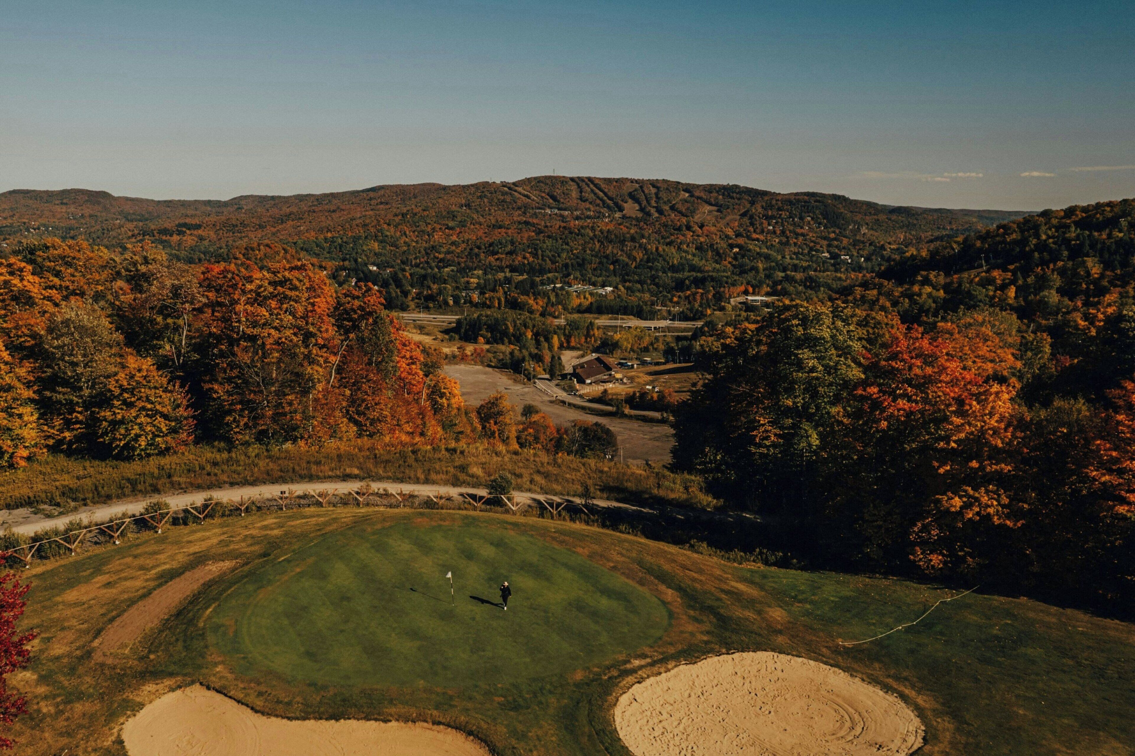 A golf course with a clear view of the surrounding forest and hills.