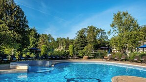 A clear blue pool surrounded by lounge chairs and umbrellas, with trees in the background. - Mont Gabriel, Sainte-Adele, a Tribute Portfolio Resort (Sainte-Adele)