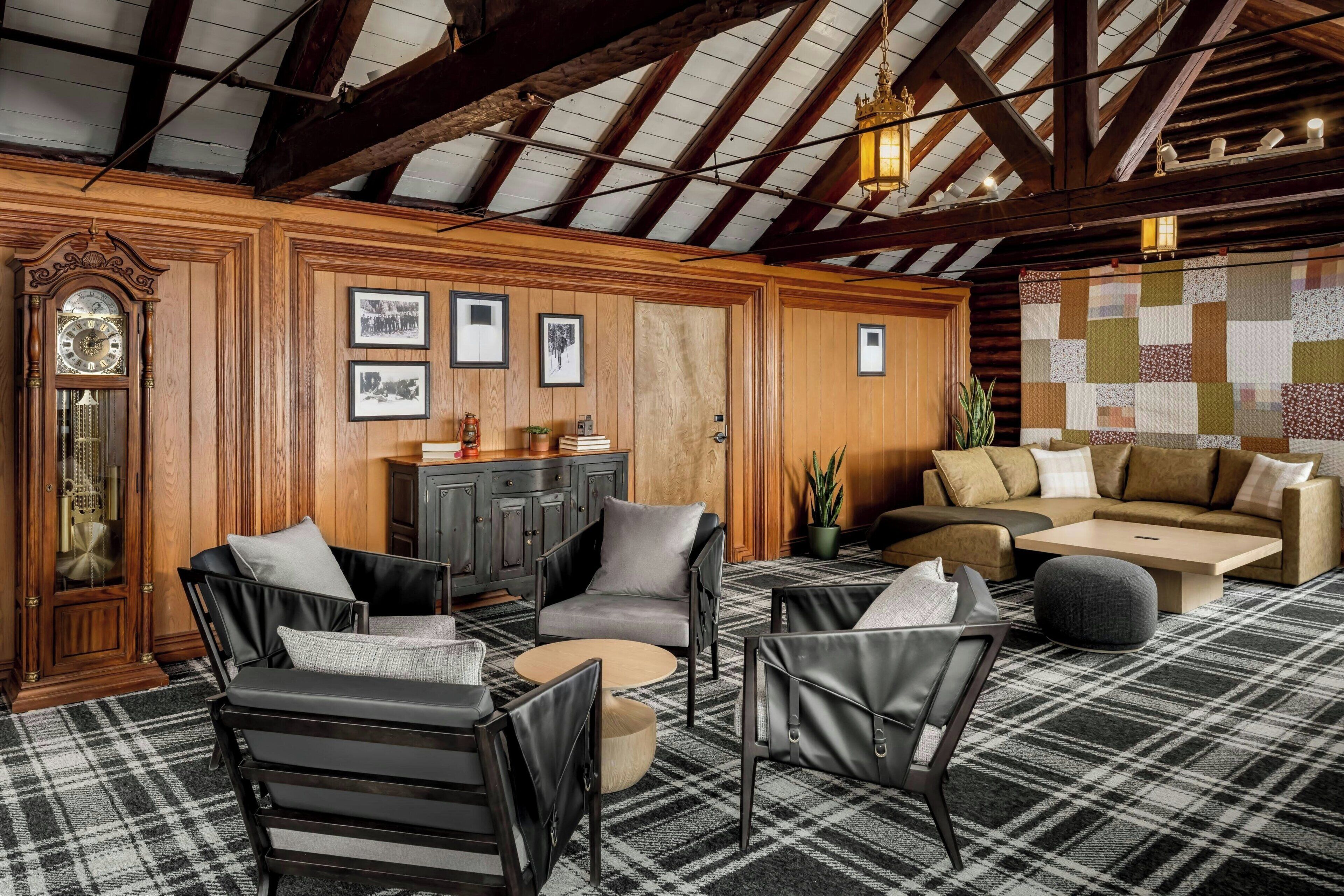 A cozy living room with wooden paneling, a large clock, and a quilted wall hanging.