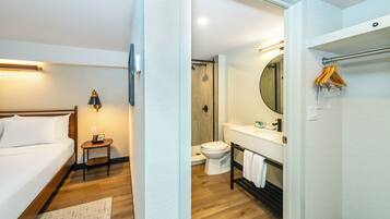 A hotel room with a bed, bedside table, lamp, and a small rug.