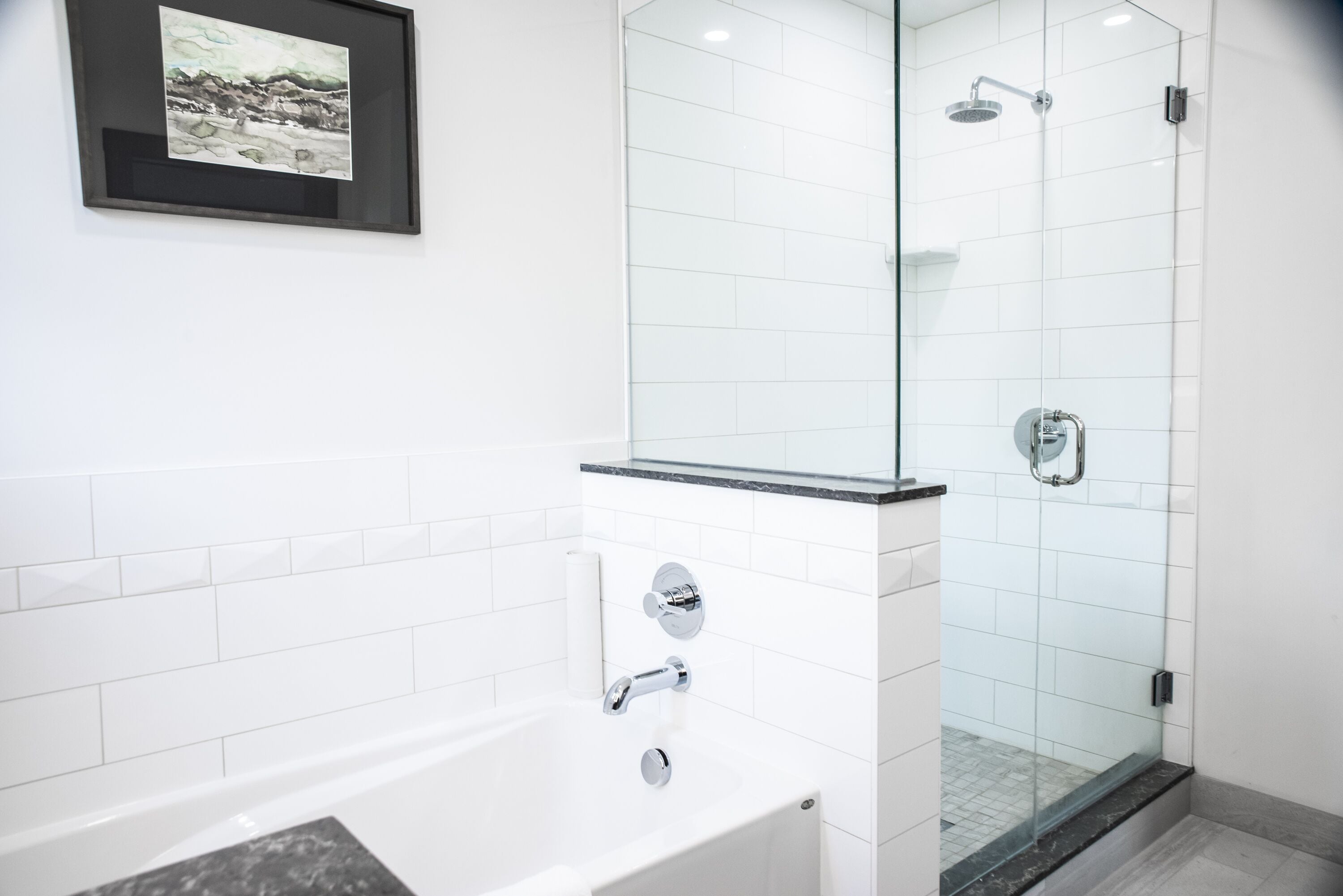 Un baño moderno con bañera, cabina de ducha de vidrio y un cuadro enmarcado en la pared.