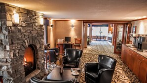 A room with a stone fireplace, leather chairs, a dining table, and a patterned carpet. - Charltons Banff (Banff)