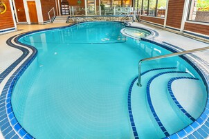 Una piscina interior con bordes de azulejos y una escalera de metal.