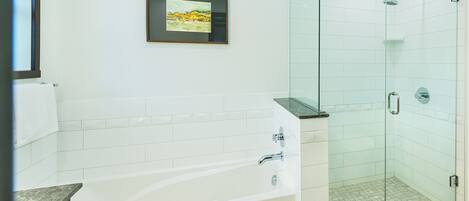A modern bathroom with a bathtub, a glass shower enclosure, and a framed picture on the wall.