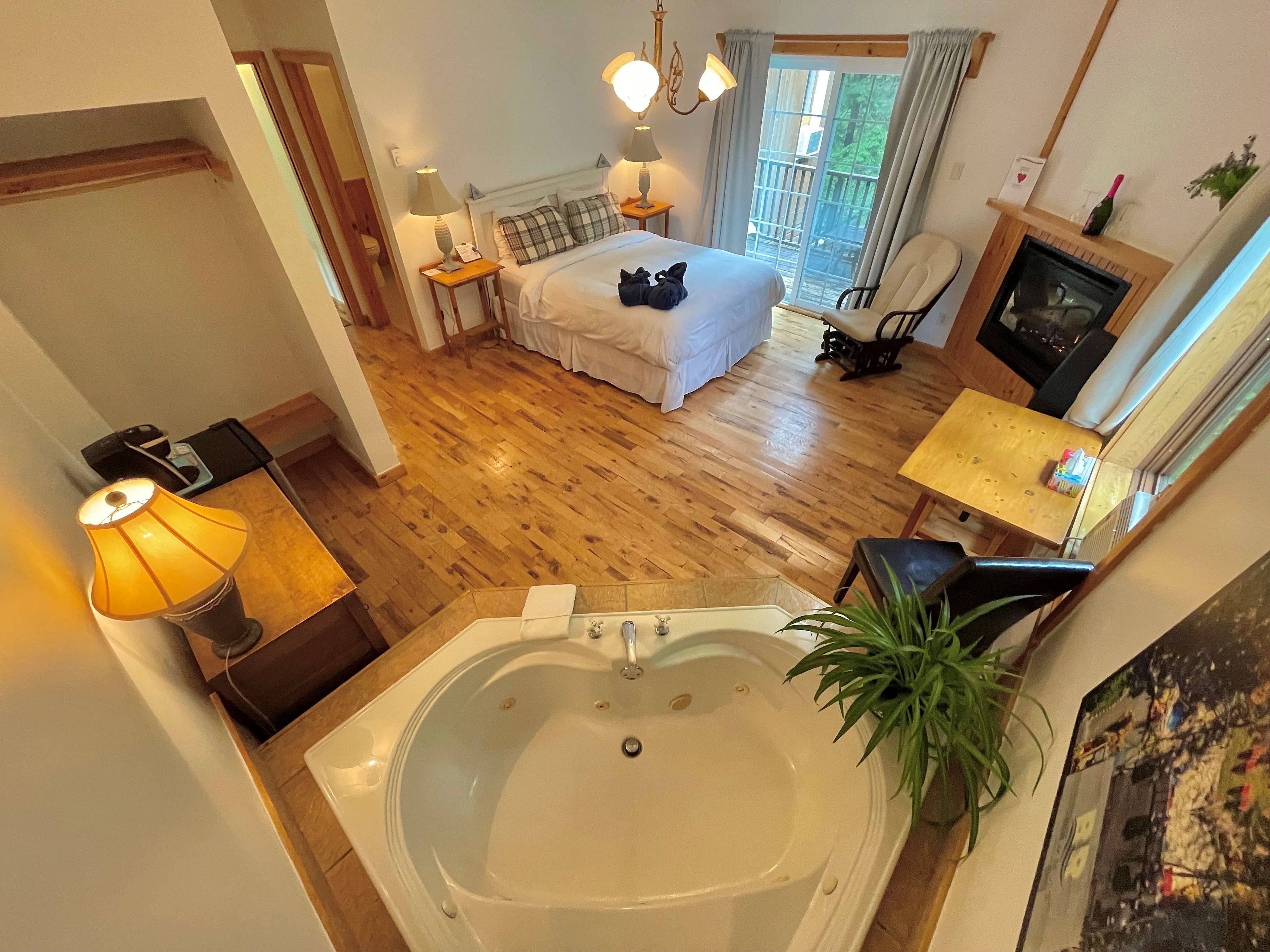 Una camera da letto con un letto grande, una zona relax con una poltrona, un caminetto e un bagno con vasca.
