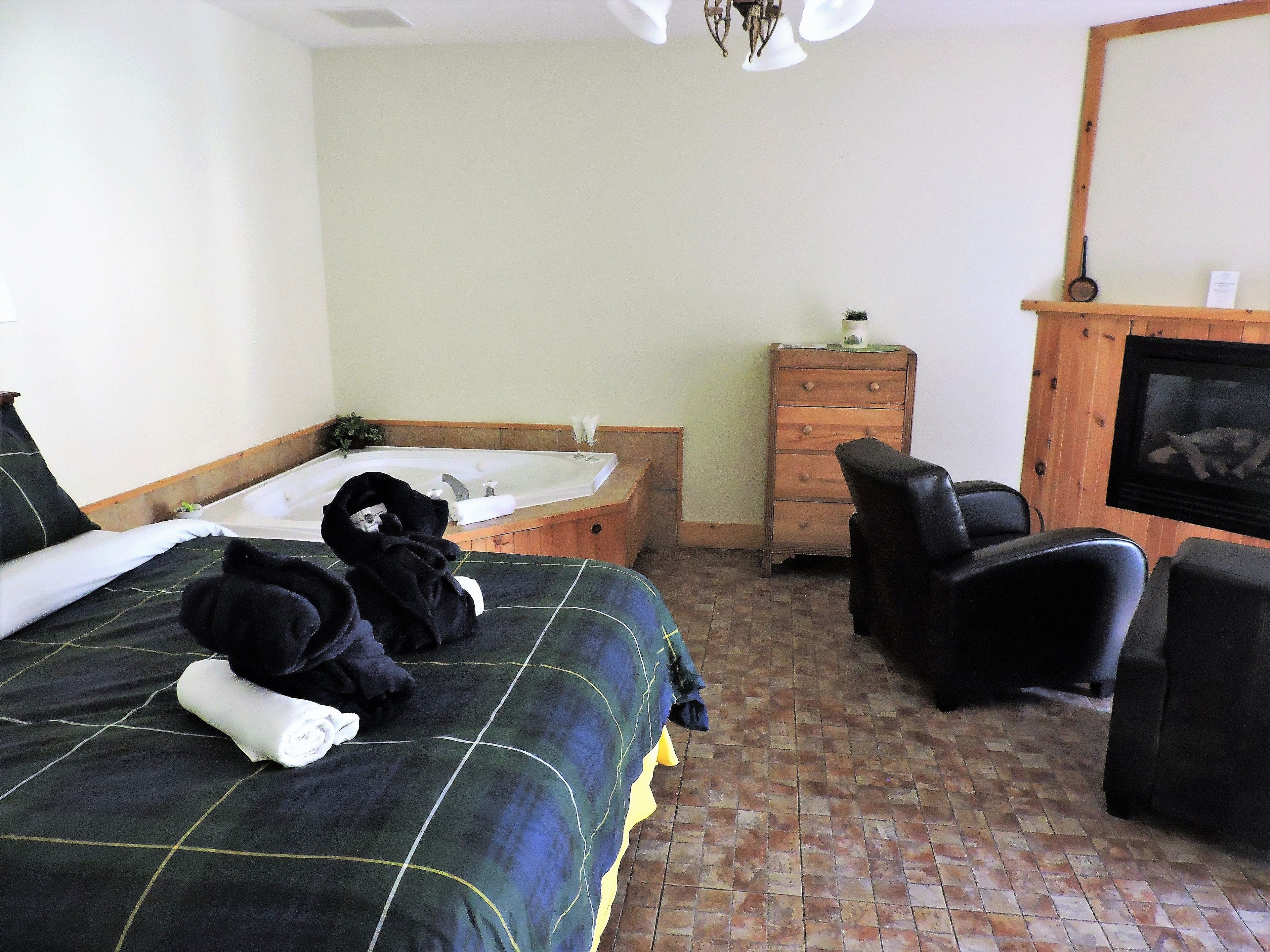 Una habitación de hotel con una cama, un aparador de madera, una televisión y una chimenea.