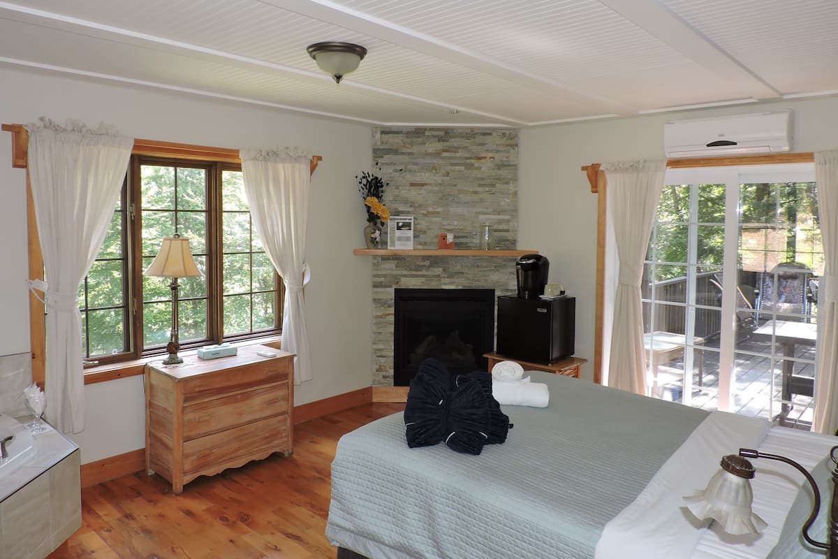 Quarto com cama, cômoda, lareira e janela com cortinas.